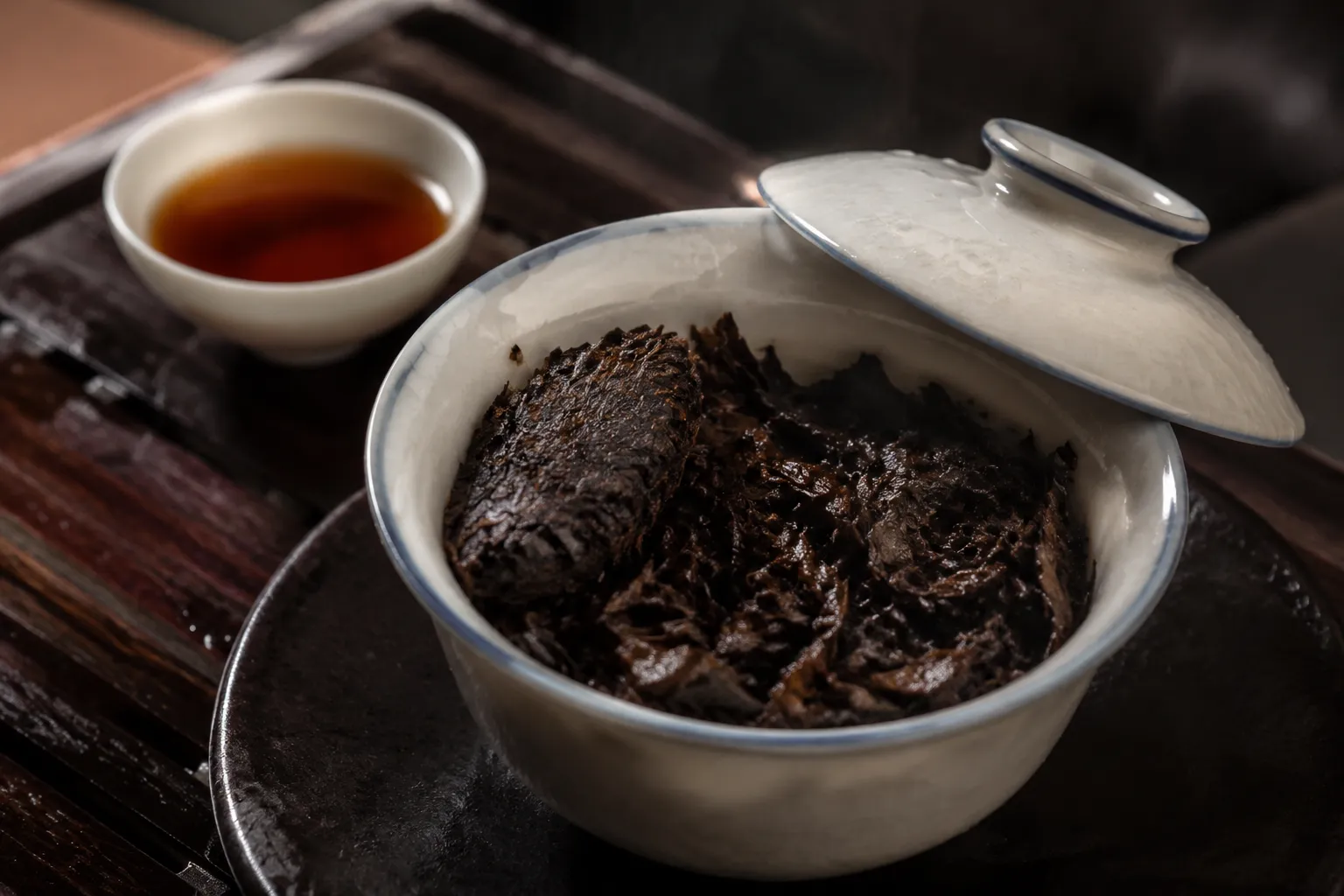 Wet compressed dark tea leaves resting in a covered brewing vessel after the first hot water pour