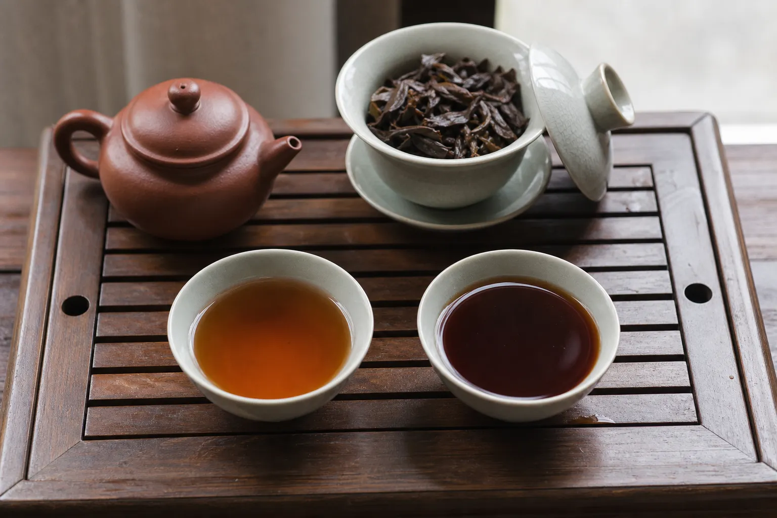 Two dark tea cups brewed from the same leaves, one shorter and one longer, used to compare depth against heaviness