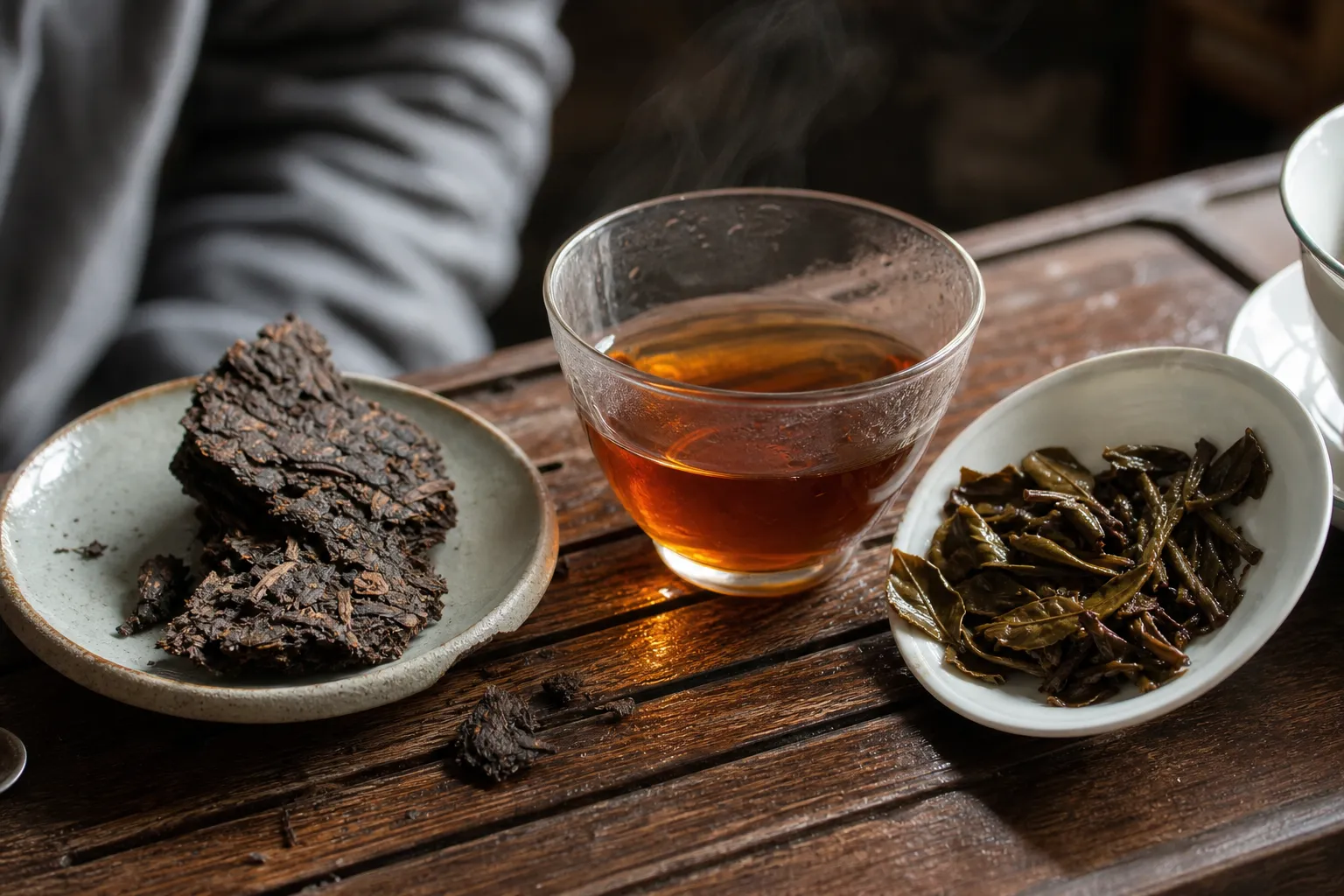 A broken piece of pu-erh cake with brewed liquor and wet leaves used to check storage aroma beyond the wrapper.