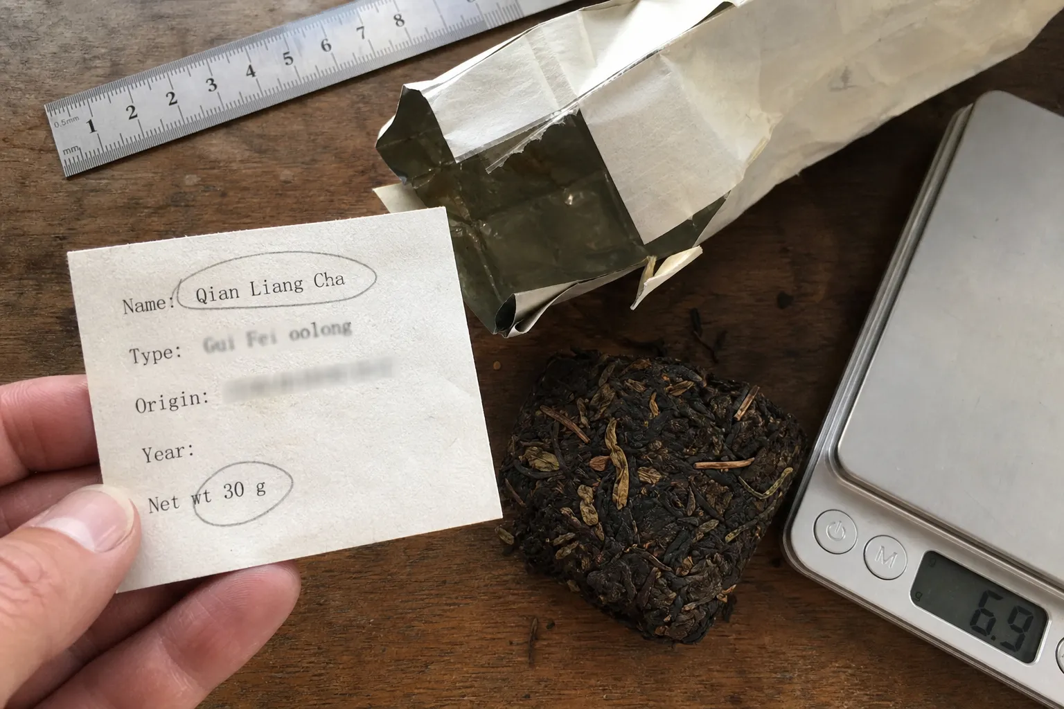 A Qian Liang Cha label being checked for the tea name, net weight, and physical form