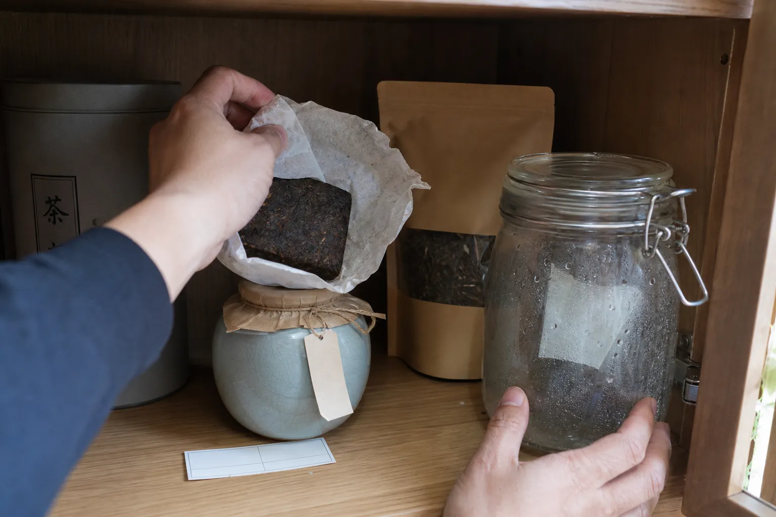 Dark tea storage containers and wrappers being checked for odor, dampness, and light exposure