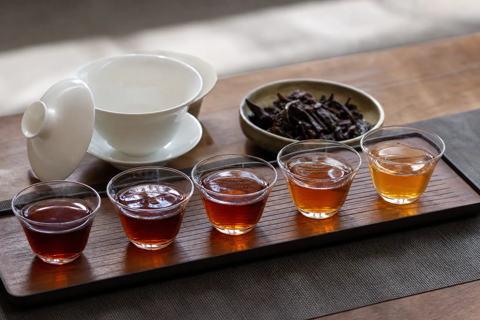 Several small cups of dark tea showing how liquor color can change from one steep to the next